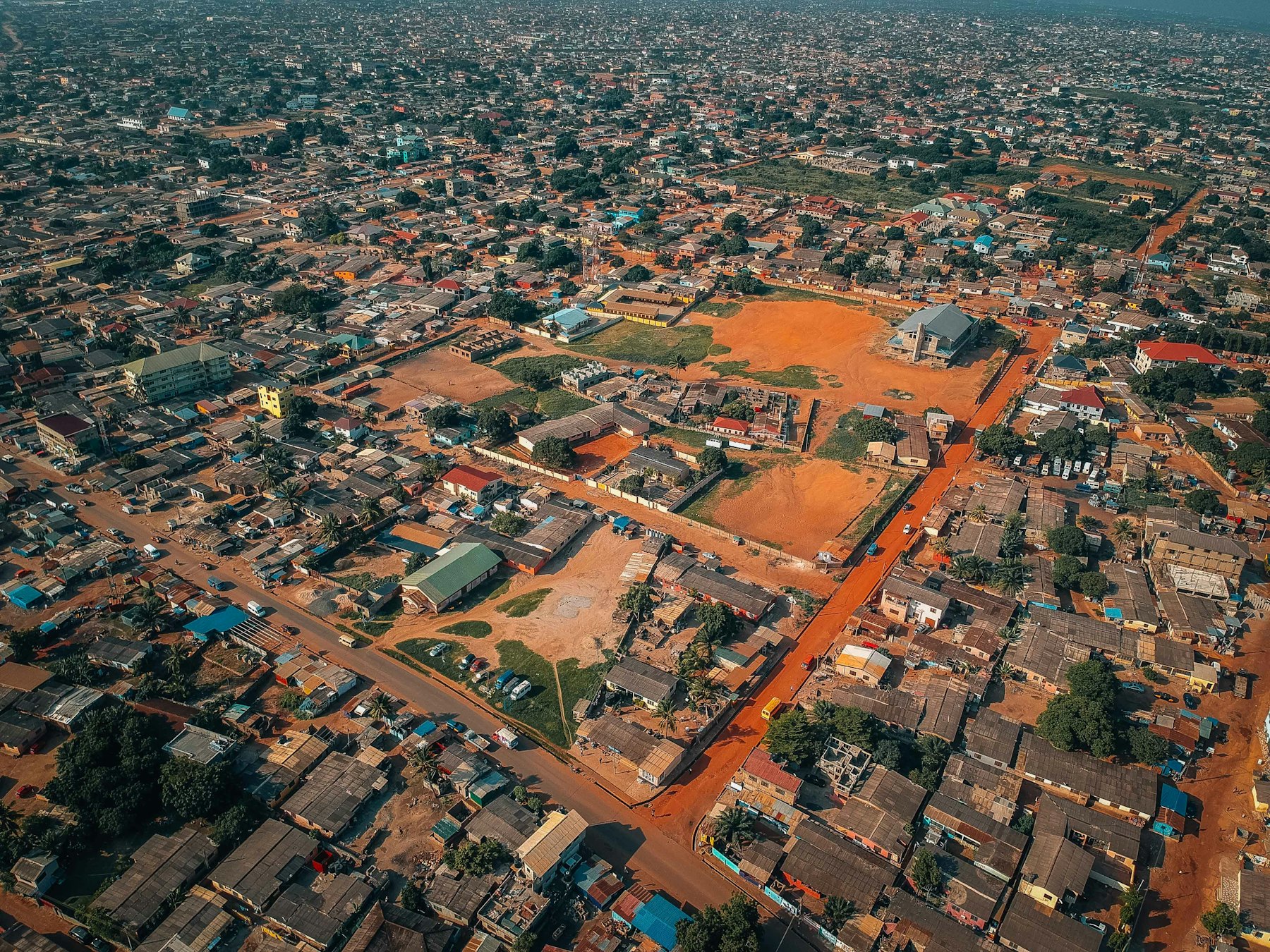 Accra from above: red laterite roads between rooftops and trees