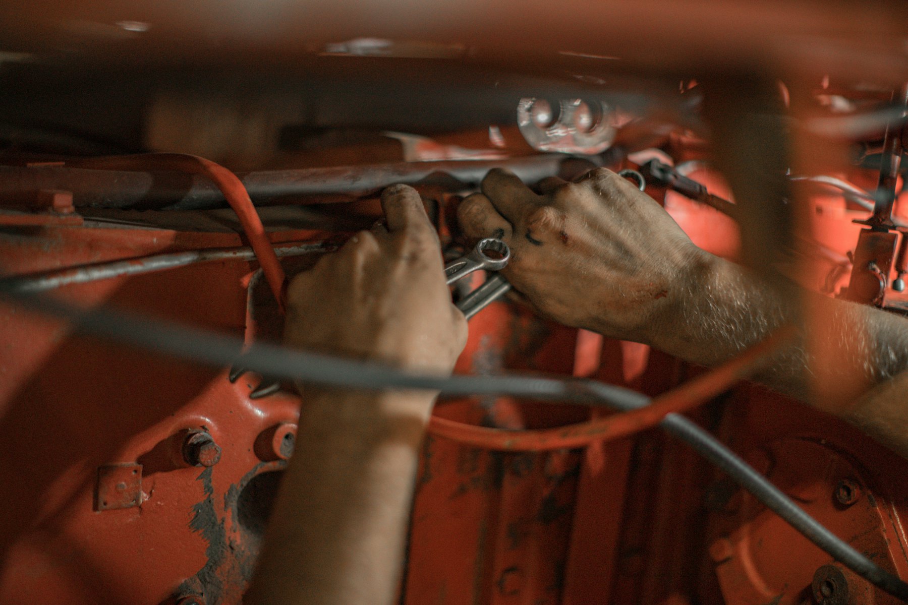 Hands tightening a bolt on a red-painted steel frame